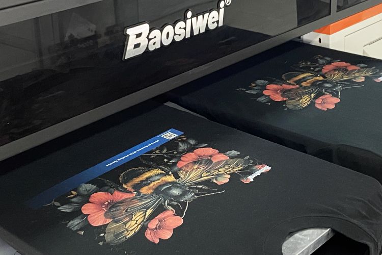 Baosiwei dual-station DTG printer printing bee designs simultaneously on black cotton T-shirts