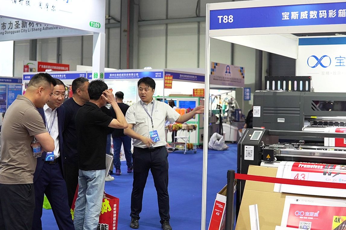 Baosiwei sales representative introducing coated paper digital printing and cutting machine to clients at Dongguan Packaging Expo.