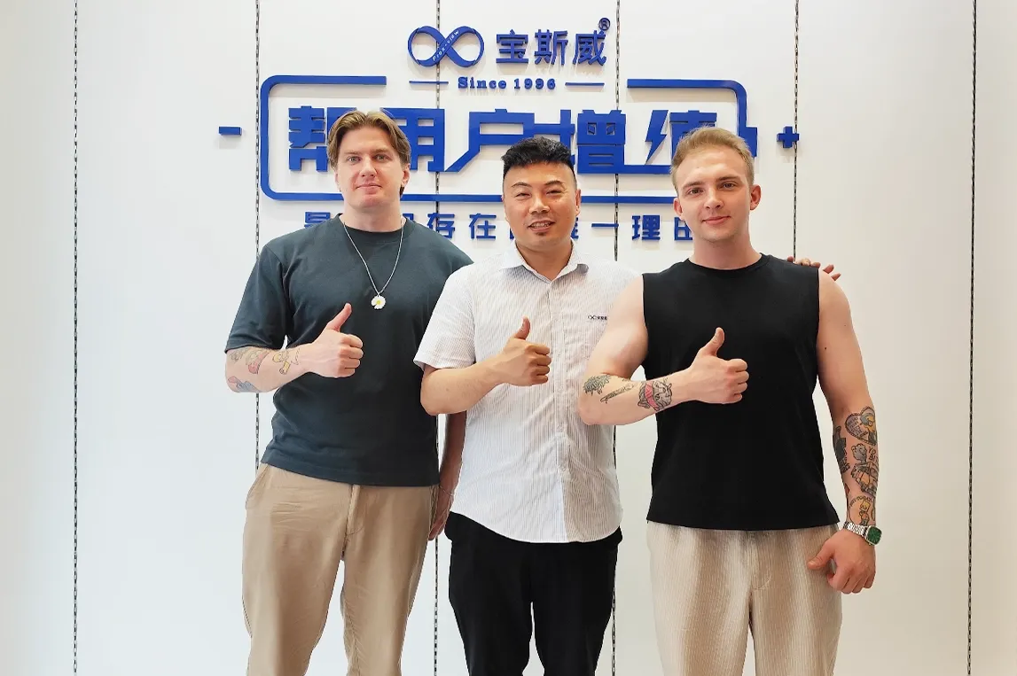 欧洲地垫客户在宝斯威工厂品牌墙前竖起大拇指，UV网带打印机演示后合影留念